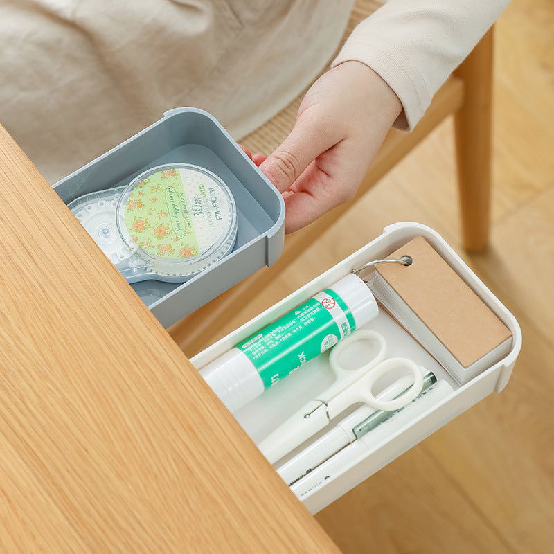 stick-on under-desk pen drawer used in a home office workspace